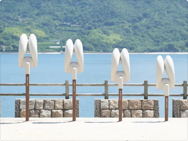 White rabbit ear-shaped objects hanging on a seaside fence