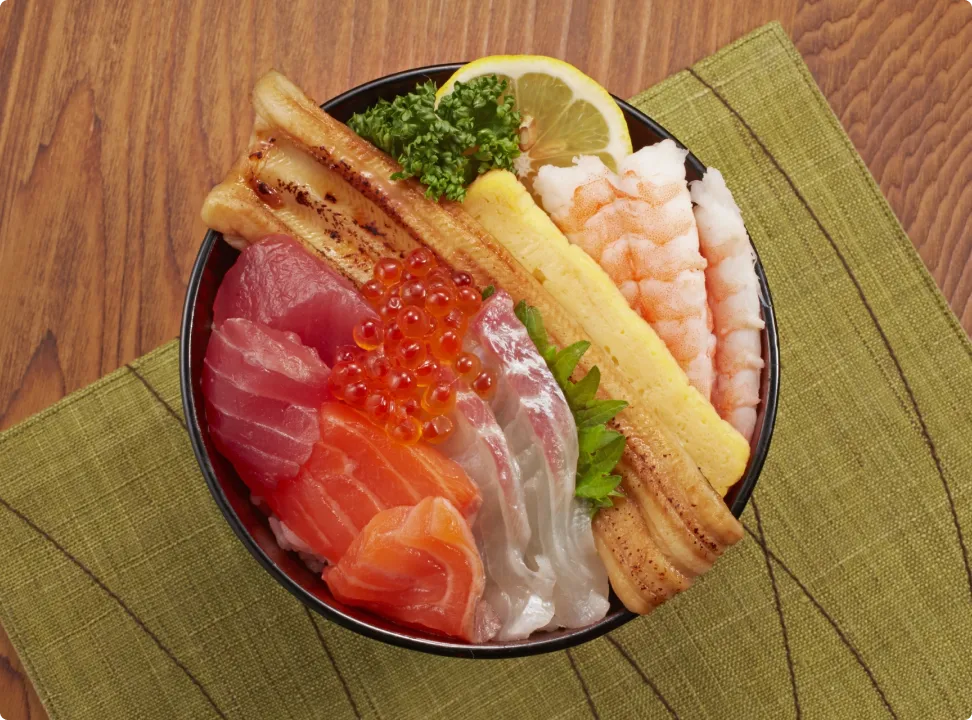 A luxurious seafood bowl topped with tuna, salmon, salmon roe, shrimp, and tamagoyaki