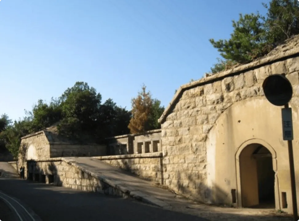 건물 그림자와 햇빛이 교차하는 높게 솟은 석벽 통로