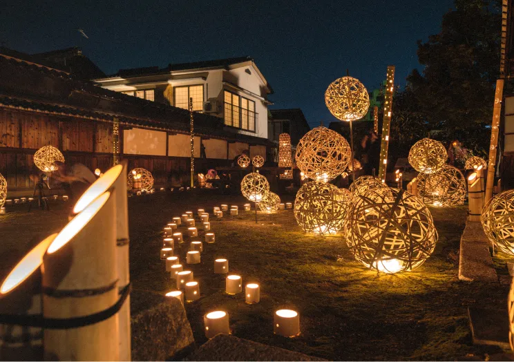 竹灯籠の柔らかな光が幻想的に路地を照らす、夜の町並み保存地区